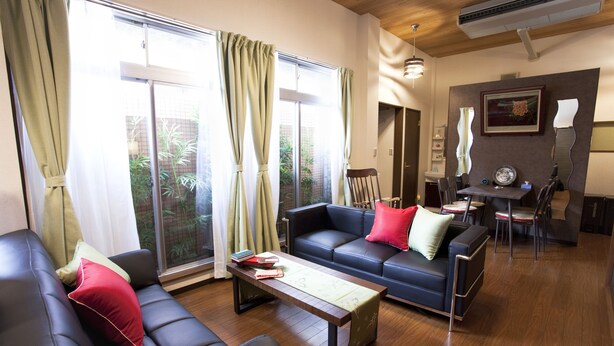 A modern living room with a sofa, a coffee table, and a dining area with a table and chairs. - Nagomi House (Tokyo)