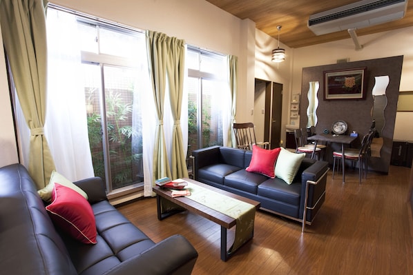 A modern living room with a sofa, a coffee table, and a dining area with a table and chairs. - Nagomi House (Tokyo)
