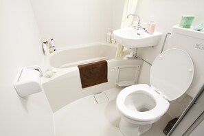 A modern bathroom with a white bathtub, sink, and toilet. - Nagomi House (Tokyo)