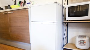 A kitchen with a white refrigerator, a microwave, and a rice cooker on a shelf. - Nagomi House (Tokyo)