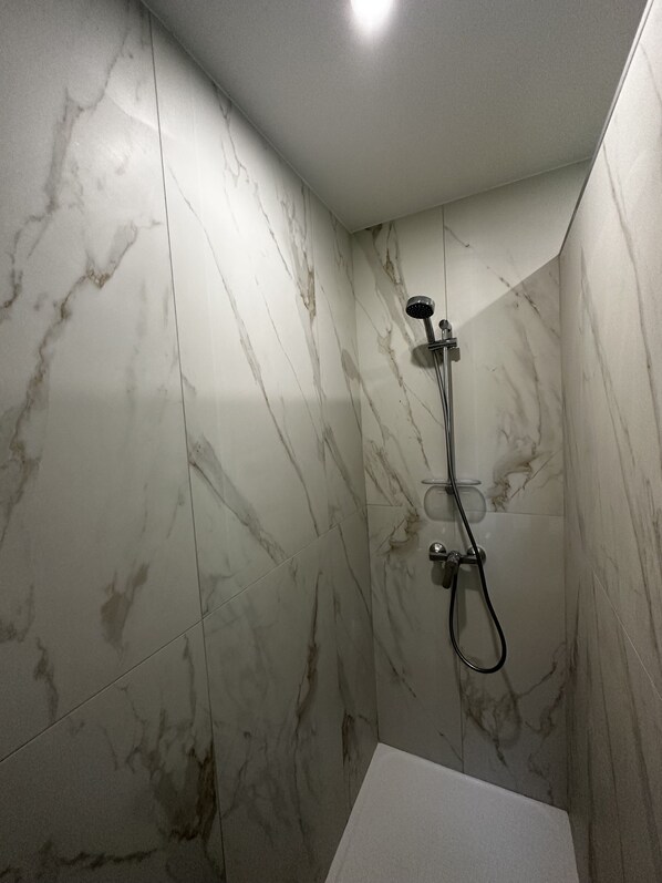 A bathroom with a shower and a toilet, both with marble walls. - In paradise, feet in the water (Biguglia)
