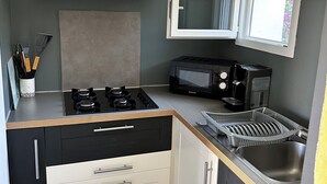 Una cocina compacta con estufa a gas, microondas y horno empotrado.