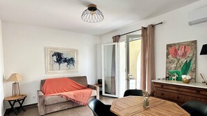 Una sala de estar moderna con un sofá, una mesa de comedor con sillas, una lámpara y obras de arte en las paredes.