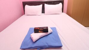 A single bed with a white headboard, two white pillows, a blue blanket, and a box of toiletries. - Kamar Keluarga Mangga Besar (Jakarta)