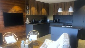 A modern living room with a sofa, two chairs, a coffee table, and a TV. - Le Portail 13 - Outstanding apartment at the foot of the slopes (LES AVANCHERS VALMOREL)