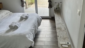 A bedroom with a bed, a small table, and a view of the outdoors. - L'Eden Corse (Biguglia)