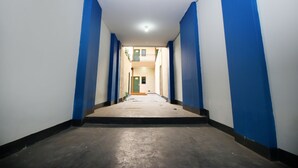 Un long couloir étroit aux murs bleus et blancs, qui mène à une porte au fond.