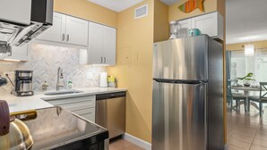 A modern kitchen with stainless steel appliances, white cabinets, and a herring wall decoration. - Cute one bedroom condo. walk to the beach and st Armand circle (Sarasota)