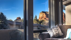 A room with a view of red rock formations, a cushioned seating area, and a metal chair. - UPSCALE Sedona VIEWS-heated POOL-golf-hot tub-Pball-tennis-fireplace-PRIVATE (Sedona)