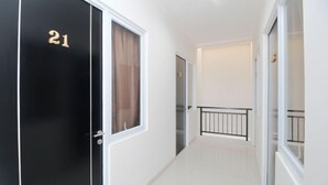 A corridor with a black door marked '21', white walls, and a tiled floor.