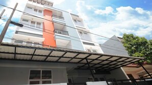 A multi-story residential building with a flat roof, balconies, and a visible power line.