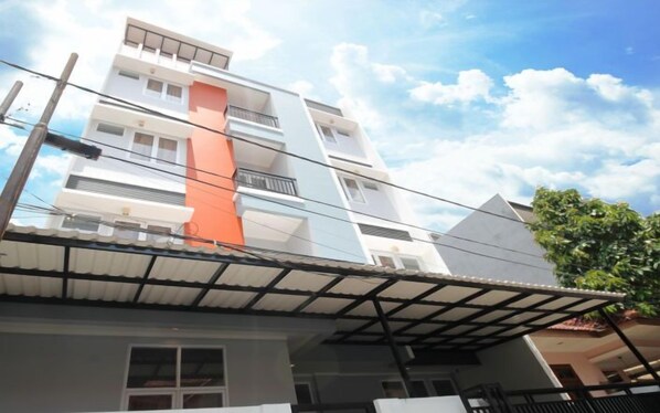Un edificio residencial de varios pisos con techo plano, balcones y una línea eléctrica visible.