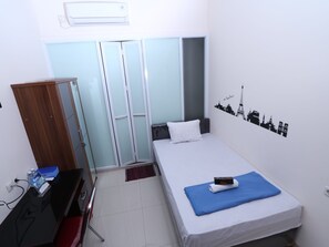 Una habitación de hotel con cama, escritorio, armario y un adorno en la pared.