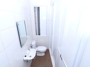 Un baño pequeño y blanco con inodoro, lavamanos y espejo.