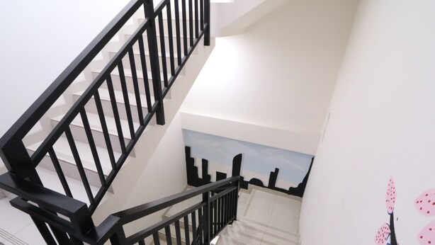 A staircase with black railings leading to a landing with a cityscape mural.