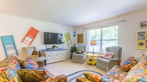 Ein gemütliches Wohnzimmer mit einer Couch, Sesseln, einem Couchtisch und einem Fernseher.