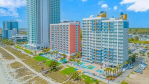 A high-rise hotel with multiple balconies, a swimming pool, and a parking area. - Atlantica 1055 (Myrtle Beach)