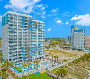 Un hotel de varios pisos con balcones, piscina y zonas ajardinadas.