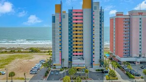 A multi-story hotel with balconies, a parking lot, and a beach view. - Atlantica 1055 (Myrtle Beach)