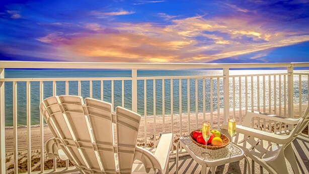 A balcony with two chairs, a table with fruit and drinks, and a view of the ocean. - Atlantica 1055 (Myrtle Beach)