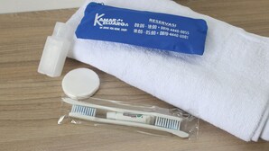 A white towel with a blue label, a toothbrush, and a tube of toothpaste on a wooden surface. - Kamar Keluarga Kampung Bali III Syariah (Jakarta)