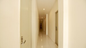 A corridor with a tiled floor and white walls. - Kamar Keluarga Kampung Bali III Syariah (Jakarta)
