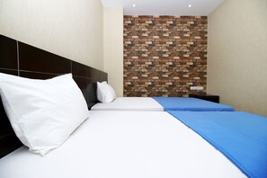 Una habitación de hotel con una cama, una pared de ladrillo y una mesita de noche.