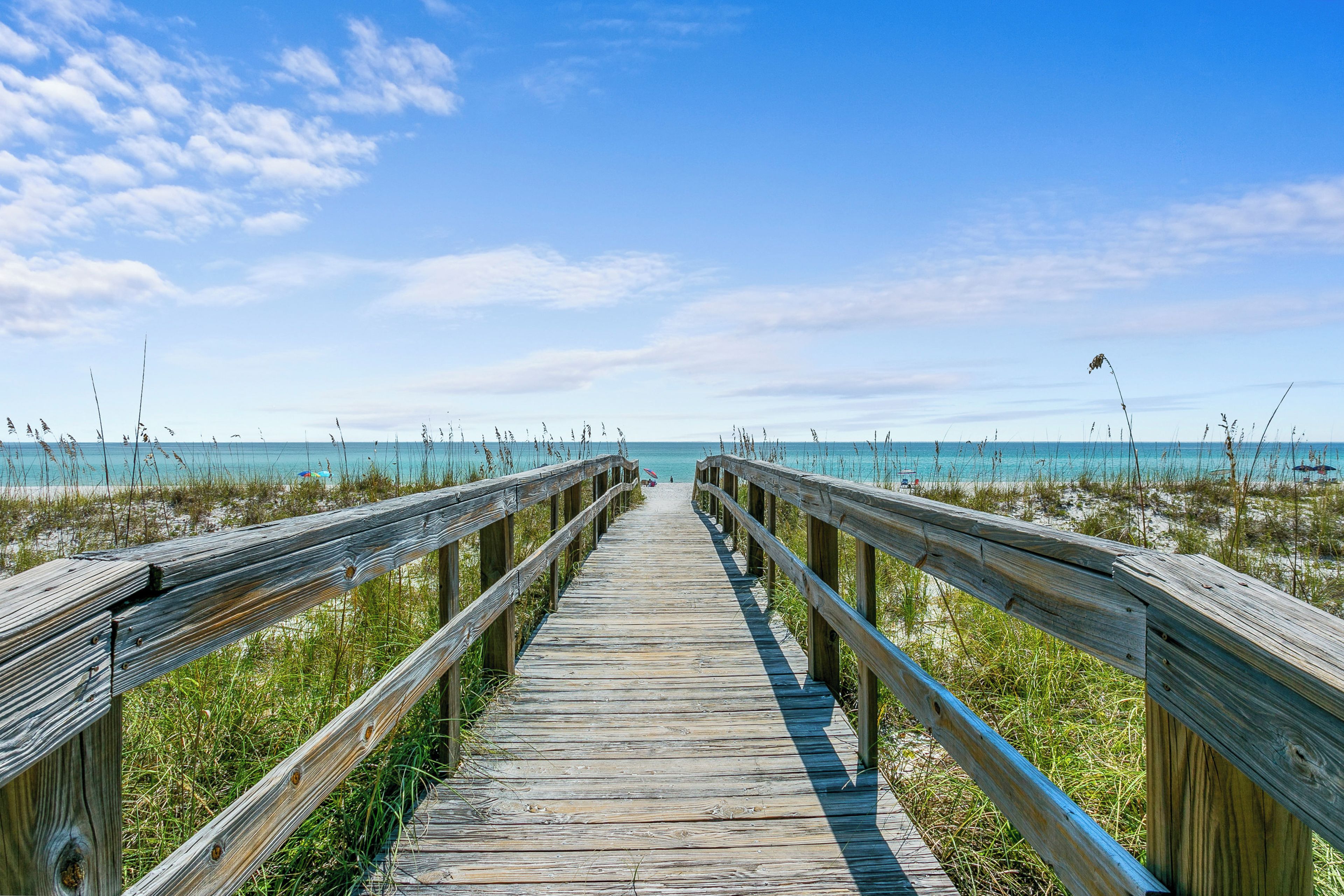 A wooden boardwalk leading to a beach with clear skies.