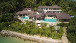 A large resort with multiple buildings, a central pool, and lush tropical surroundings. - Luxury Beach Front Noble House Villa (Wichit)