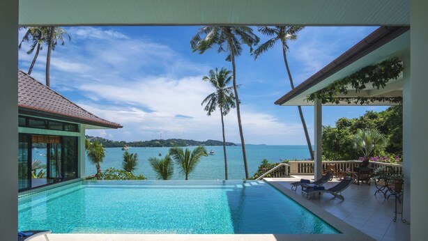A pool with a view of the sea and palm trees. - Luxury Beach Front Noble House Villa (Wichit)