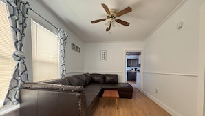 Uma sala de estar moderna com um sofá modular, uma mesa de centro de madeira e um ventilador de teto.