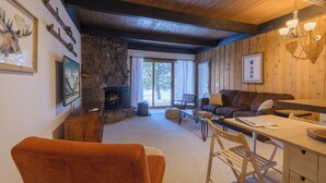 A cozy living room with a fireplace, wooden walls, and a stone accent wall.