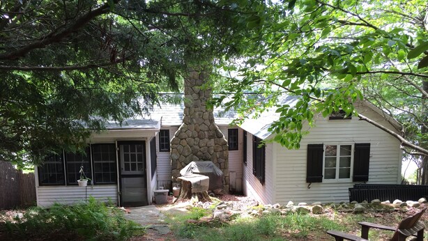 A rustic cabin with a stone chimney, a wooden deck, and a stone pathway leading to the entrance. - Lake front cottage with "million dollar" view, close to Bethel Woods (Smallwood)