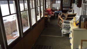 A room with large windows, a wooden interior, a table with chairs, and a small heater. - Lake front cottage with "million dollar" view, close to Bethel Woods (Smallwood)