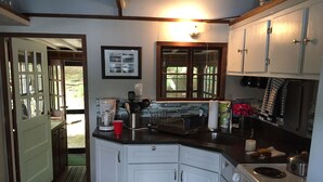 A kitchen with white cabinets, a stove, and a coffee maker. - Lake front cottage with "million dollar" view, close to Bethel Woods (Smallwood)
