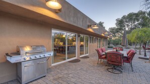 An outdoor patio with a stainless steel grill, a dining table with chairs, and a glass door leading to an indoor area. - STARFIRE Golf VIEW, Pvt POOL w/opt Heat, Putting Green, Fire Pit, 10 mins to Old Town (Scottsdale)