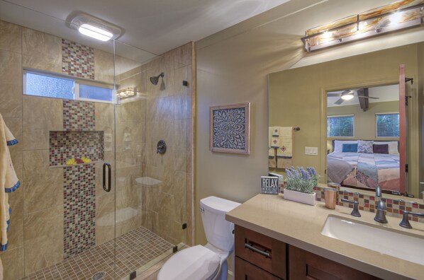 Une salle de bain avec une douche à parois de verre, des toilettes, un lavabo et un grand miroir.