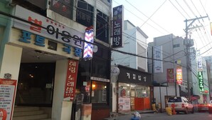 A street view with various storefronts, including a visible sign for a rental service and a building with a sign that reads "Jeico Electric Gear Rental Service". - Friends of Loft - Hostel (Tongyeong)