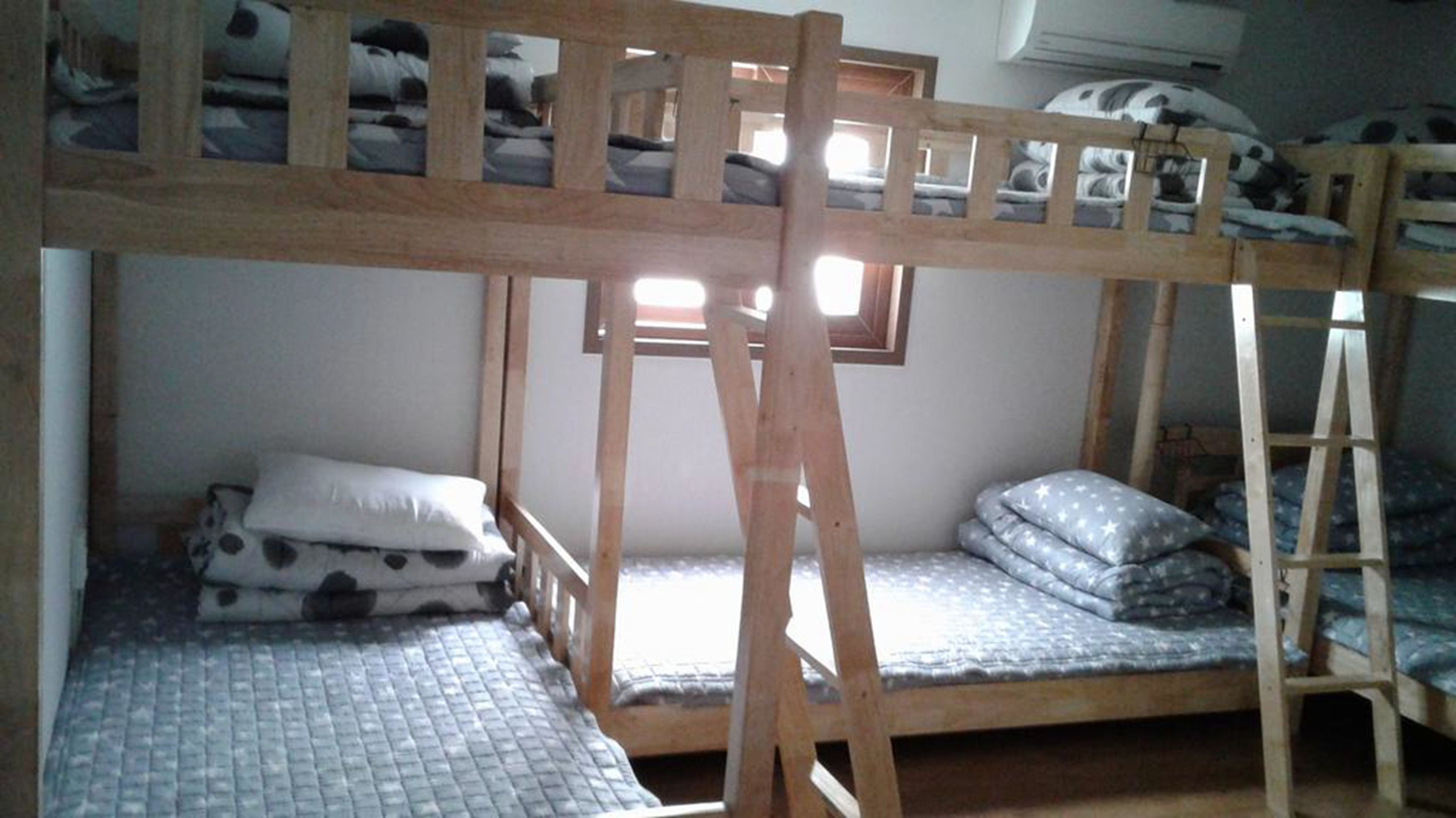 Habitación con literas, una ventana, una escalera y una mesita pequeña.