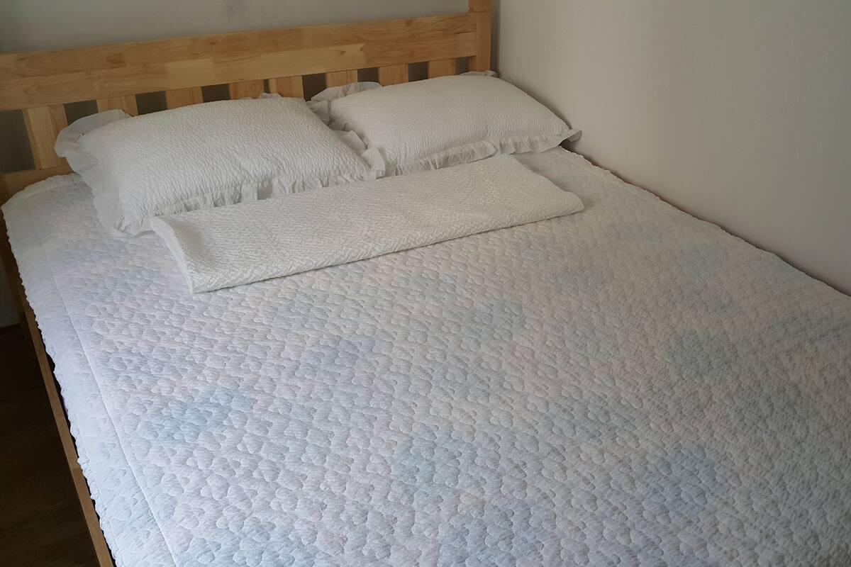 A bed with a wooden headboard, white bedding, and two pillows.