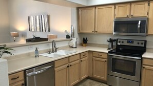 A modern kitchen with stainless steel appliances, wooden cabinets, and a white countertop. - One Story w/Htd Comm Pool & Spa: GOLF & Trails Nearby, Walk to Dine & Shop, Indoor Shuffleboard (Mesa)