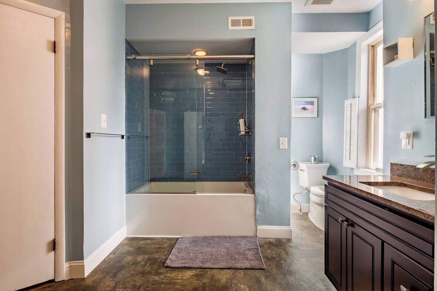 A modern bathroom with a glass-enclosed shower, a bathtub, and a vanity with a sink and mirror.
