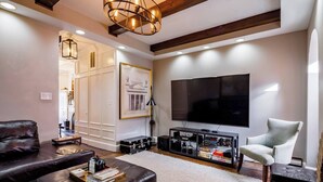 Una sala de estar moderna con un televisor de pantalla plana grande, muebles de cuero y una estantería.