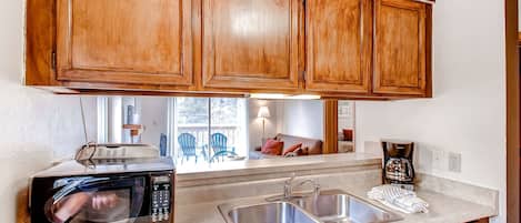 A kitchen with wooden cabinets, a microwave, a sink, and a coffee maker.