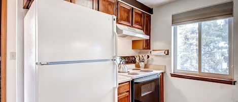 Una cocina con armarios de madera, un refrigerador blanco, una estufa y un horno.