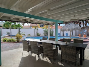 Un espace piscine extérieur doté d’un patio couvert, de chaises longues et d’une table.