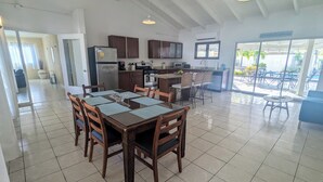 A spacious kitchen with modern appliances, a dining area with a large table and chairs, and a view of the outdoor pool area.