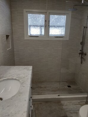 Une salle de bain équipée d’une douche, d’une baignoire et d’un meuble-lavabo avec un évier.