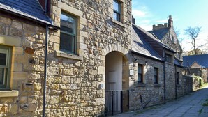 A stone building with a traditional architectural style, featuring a stone facade, multiple windows, and a visible entrance. - 2 bedroom accommodation in Alnwick (Alnwick)