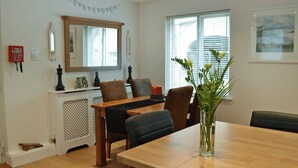 A dining area with a wooden table, chairs, a vase with greenery, and a fireplace with chess pieces. - 2 bedroom accommodation in Alnwick (Alnwick)